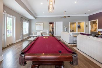 A pool table is in the middle of a room with a fan and a couch.